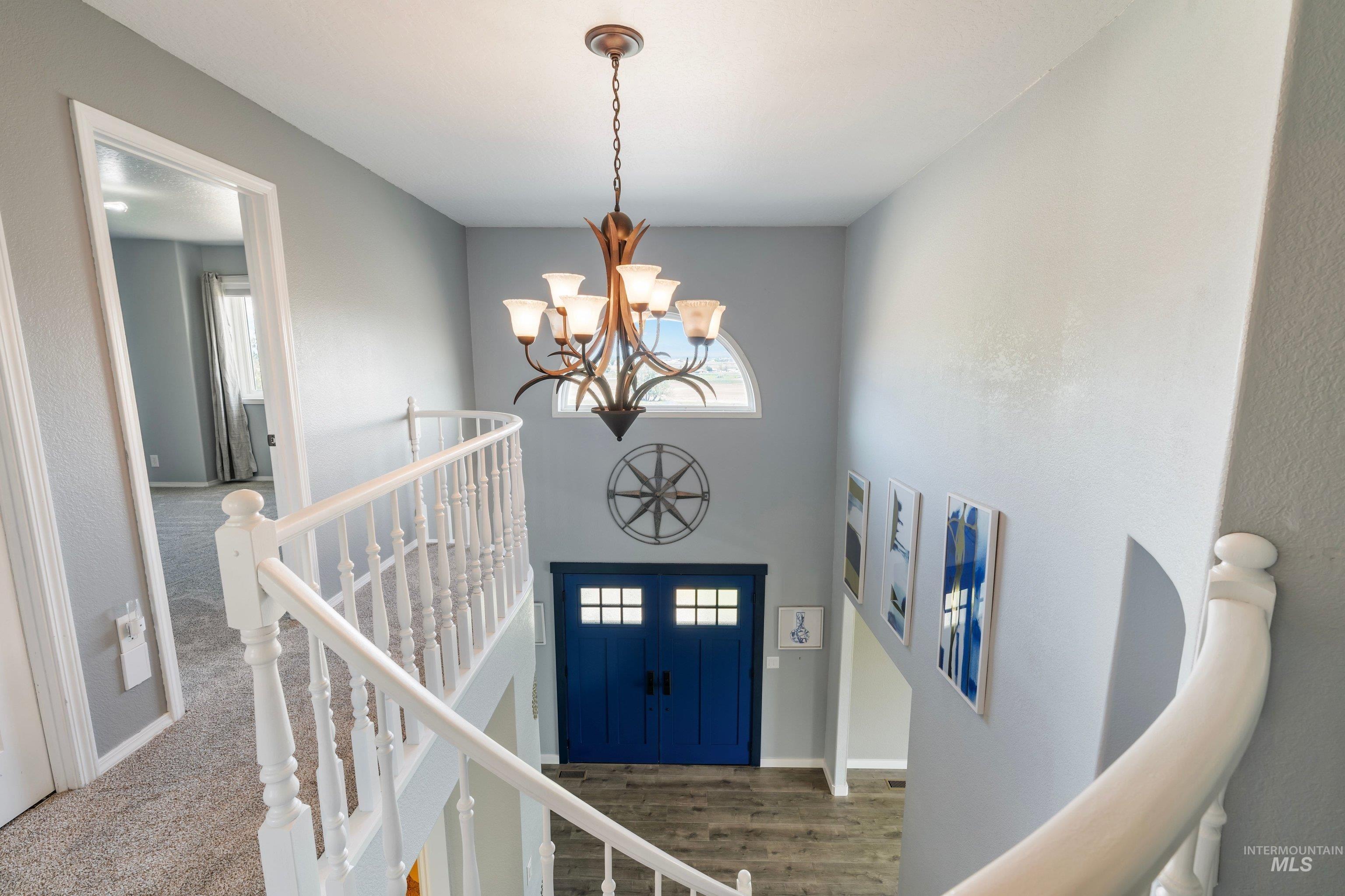 7657 Track Road Nampa, ID 83686 - Photo 19 of 49 Two-story entryway featuring a prominent chandelier, arched transom window, and a vibrant blue front door with glass lites