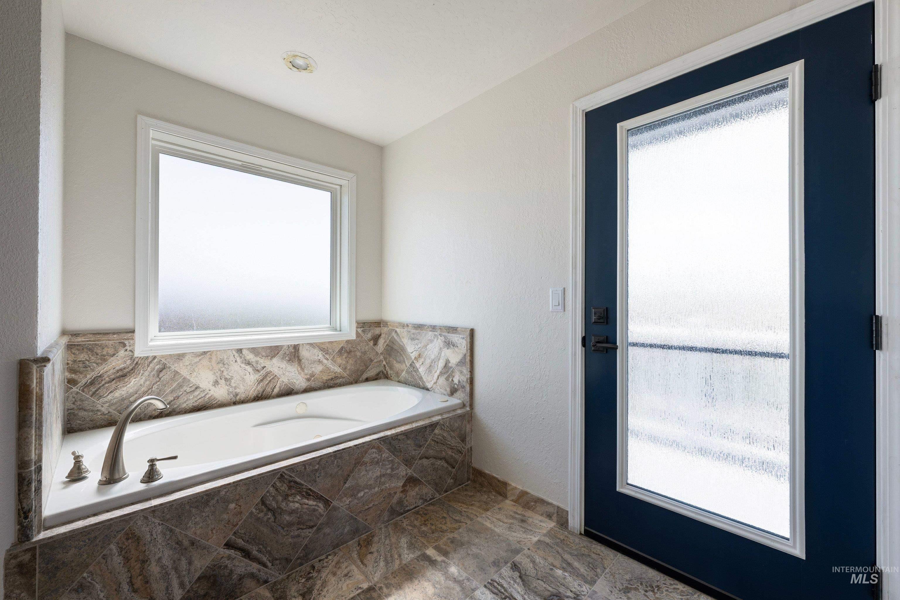 7657 Track Road Nampa, ID 83686 - Photo 26 of 49 Soaking tub with brushed nickel fixtures, surrounded by patterned stone tile