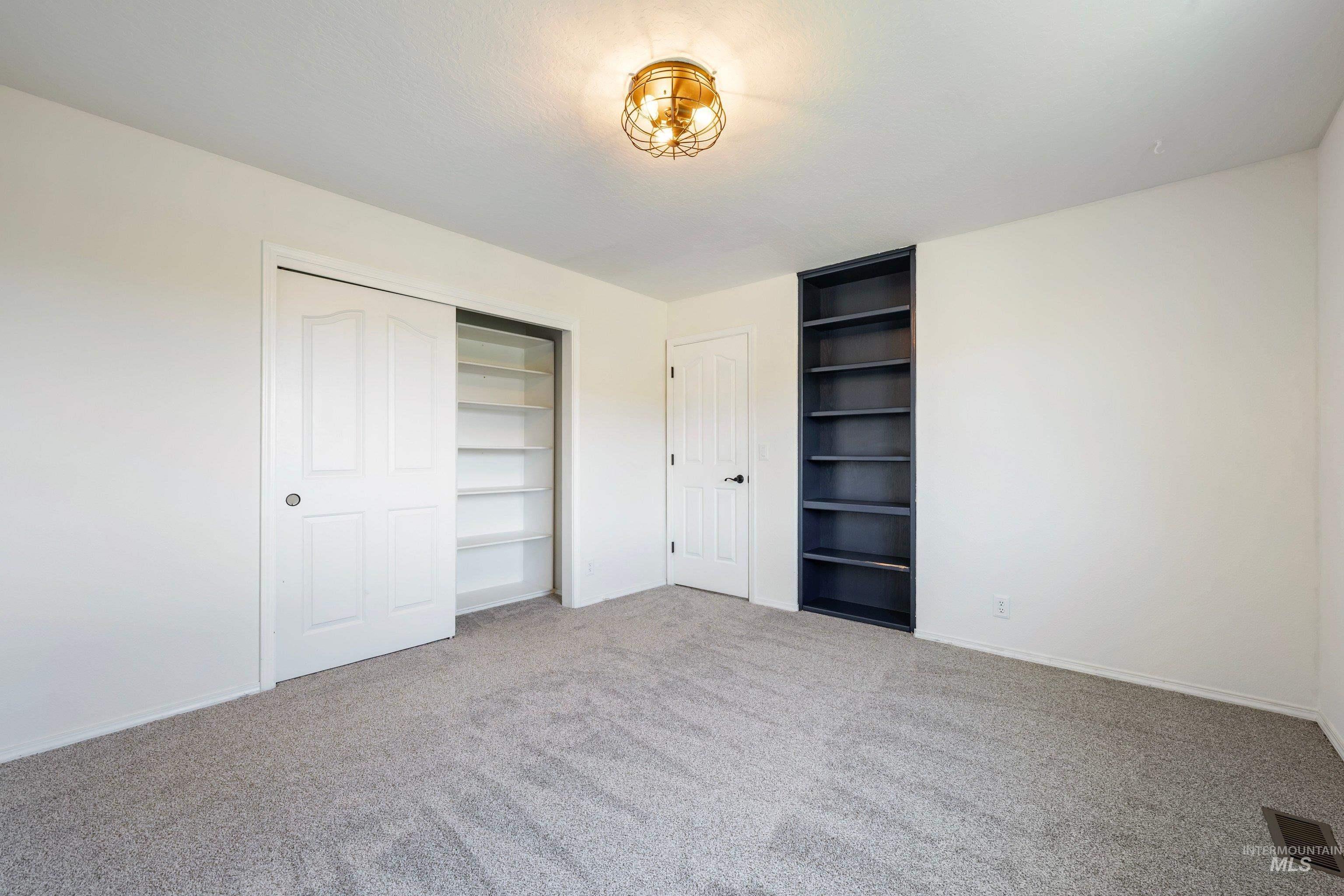 7657 Track Road Nampa, ID 83686 - Photo 28 of 49 Carpeted room featuring a ceiling-mounted light fixture, white walls, built-in shelving, and a closet with sliding panel doors