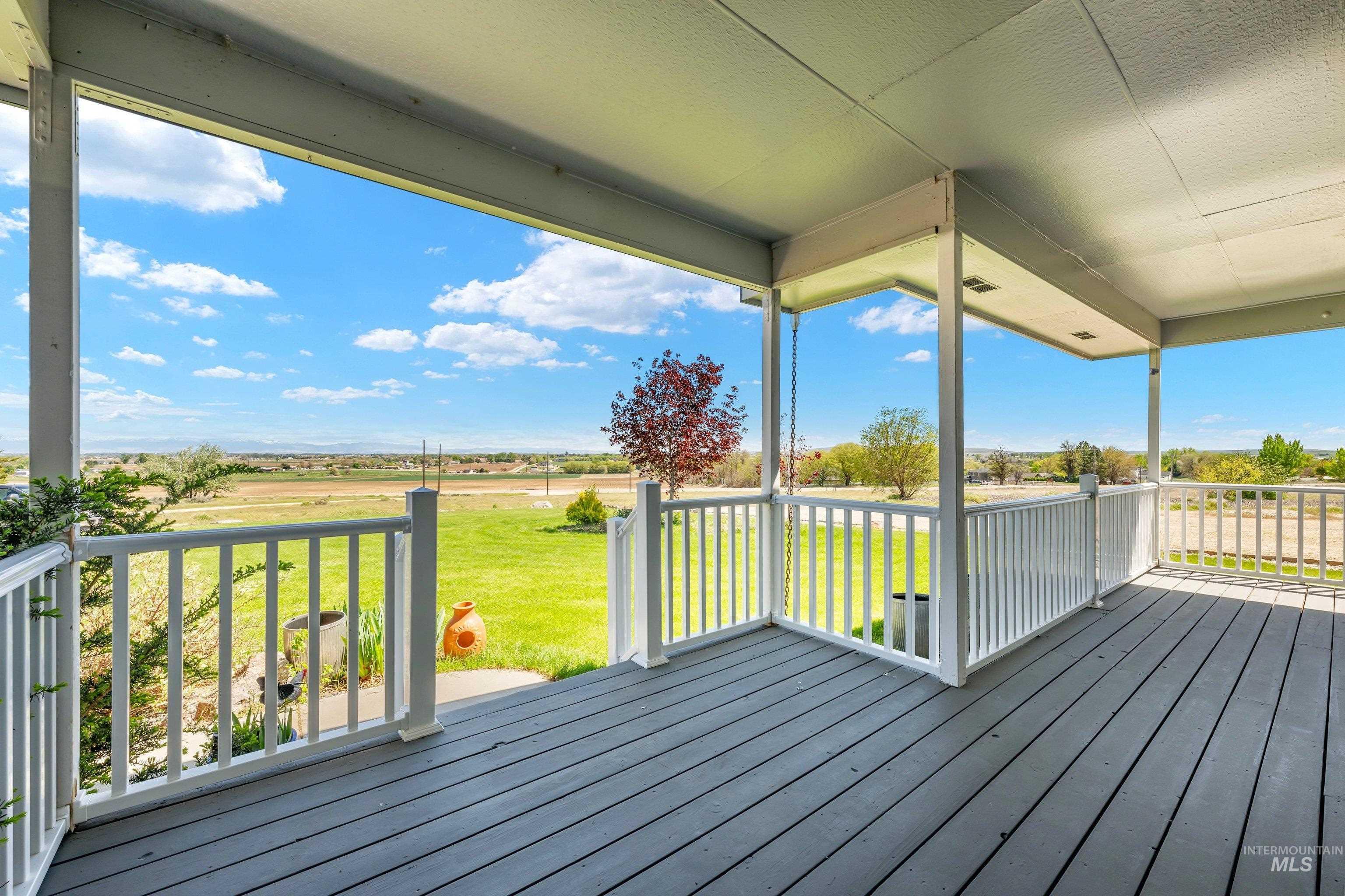 7657 Track Road Nampa, ID 83686 - Photo 3 of 49 Covered outdoor porch featuring wood-finish decking, white baluster railings, and structural support columns