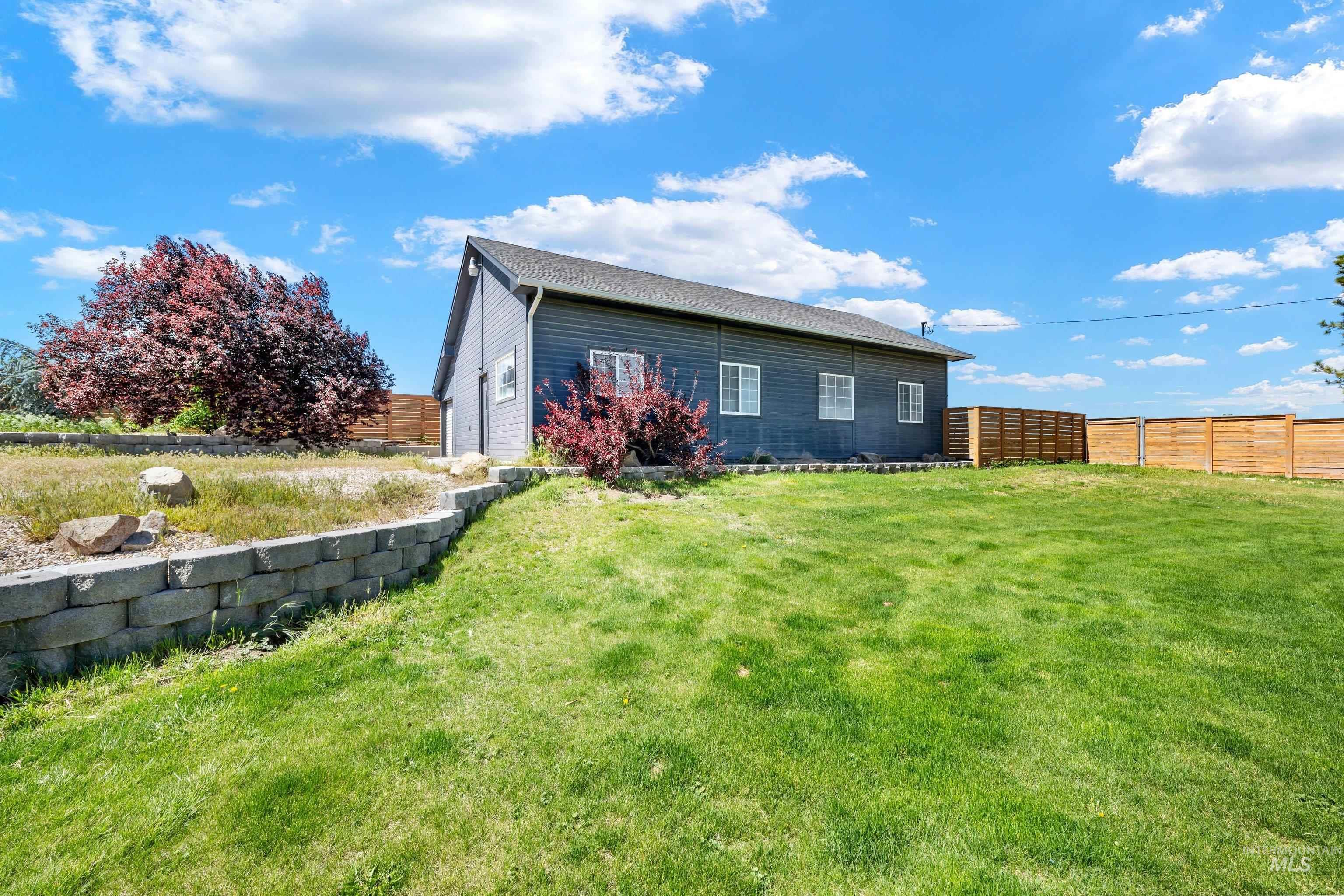 7657 Track Road Nampa, ID 83686 - Photo 31 of 49 Expansive green lawn with a retaining wall, accented by mature trees and shrubs