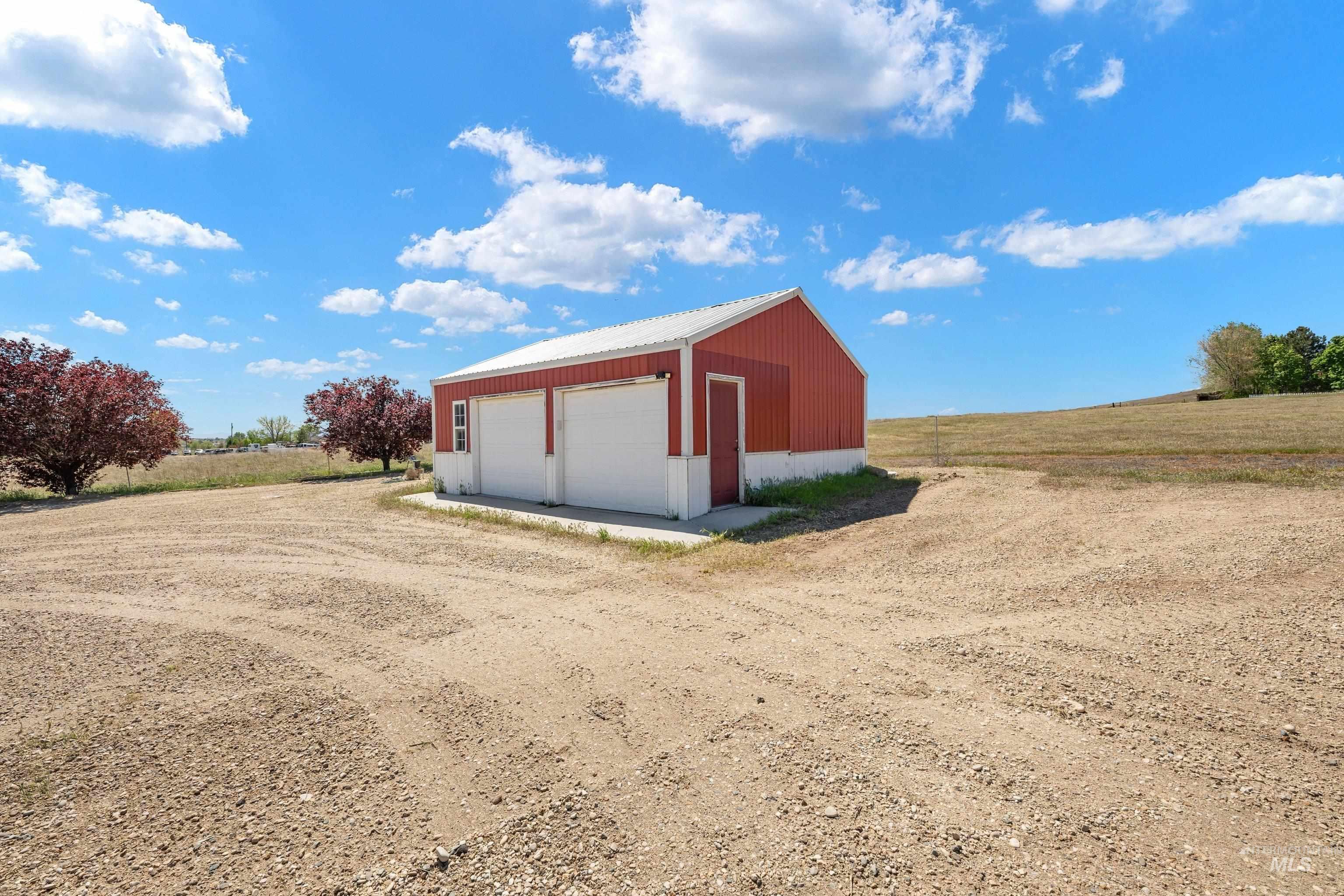 7657 Track Road Nampa, ID 83686 - Photo 32 of 49 Detached red barn-style structure featuring a white metal roof, two white garage doors, and a side entry door
