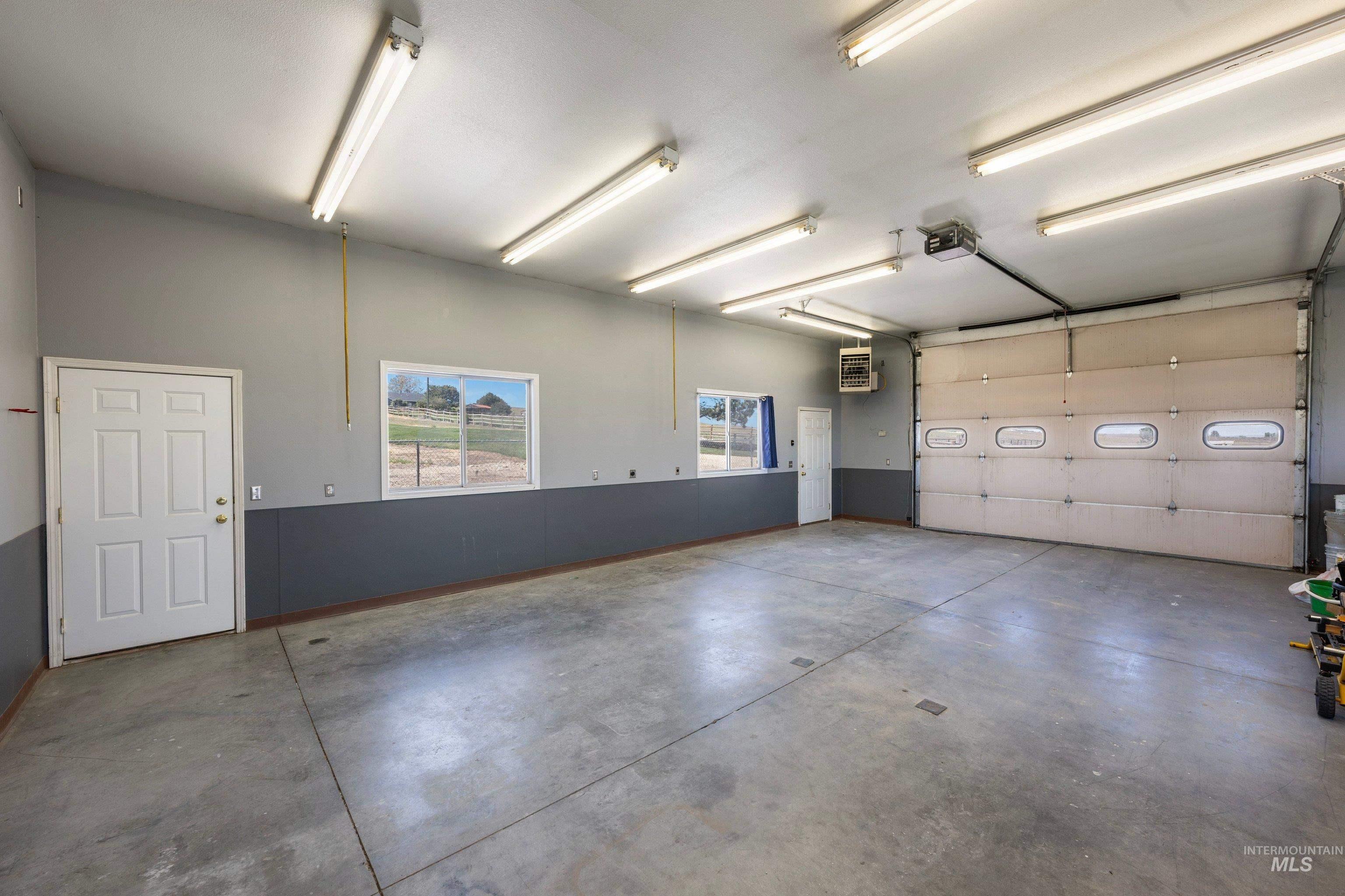 7657 Track Road Nampa, ID 83686 - Photo 35 of 49 Spacious garage featuring a large overhead door with translucent panels, multiple fluorescent lighting fixtures, and a concrete floor
