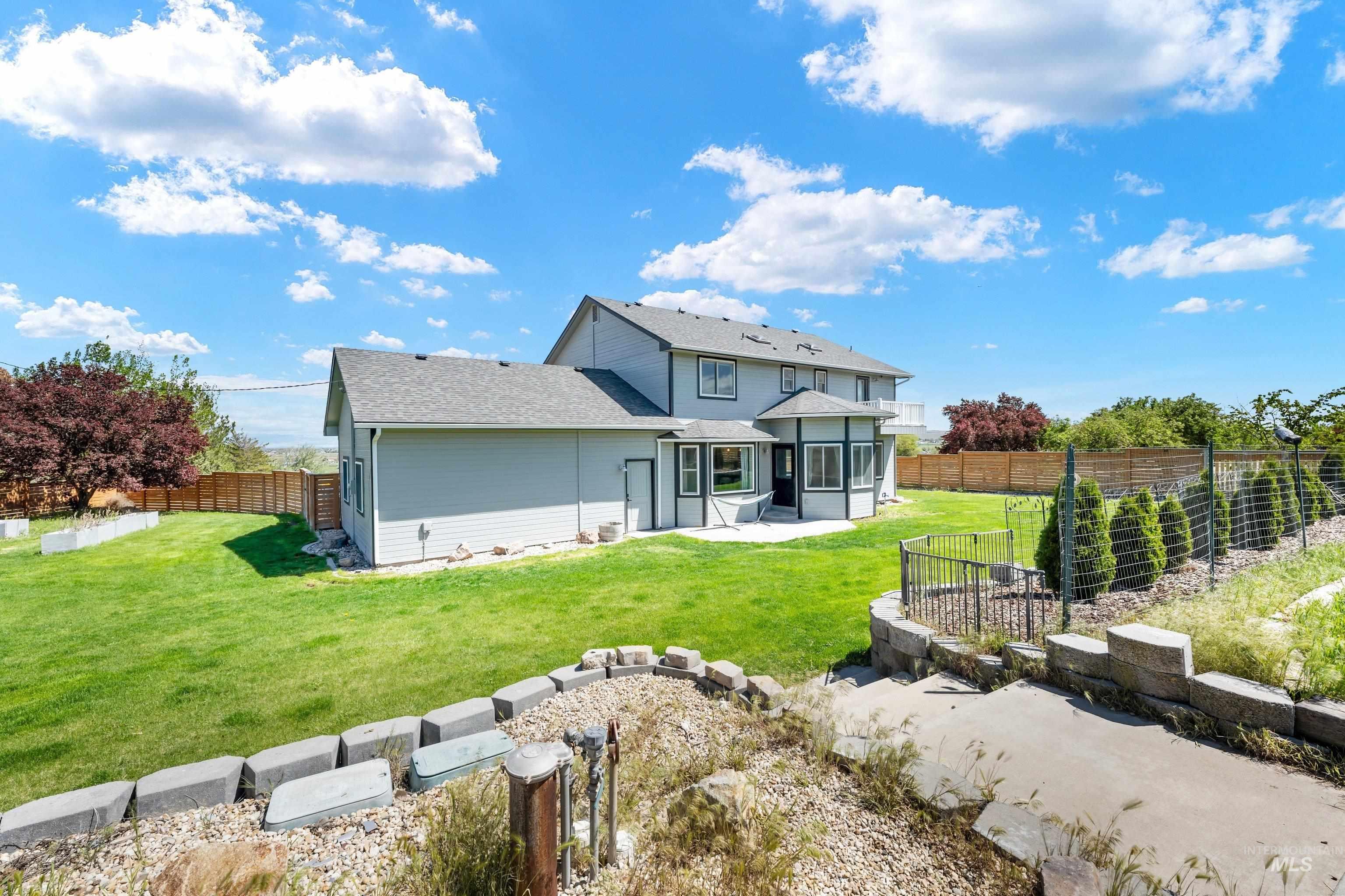 7657 Track Road Nampa, ID 83686 - Photo 36 of 49 Spacious backyard featuring a manicured lawn, tiered landscaping with block retaining walls, and a private patio area