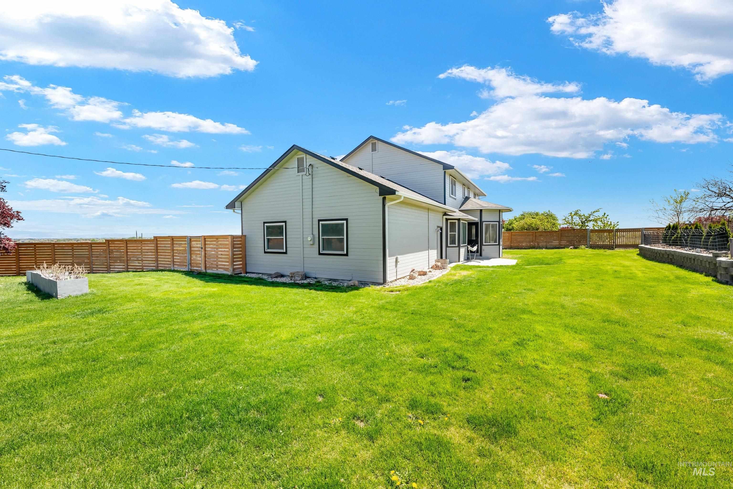 7657 Track Road Nampa, ID 83686 - Photo 38 of 49 Expansive backyard featuring a lush lawn, privacy fencing, and a built-in planter box