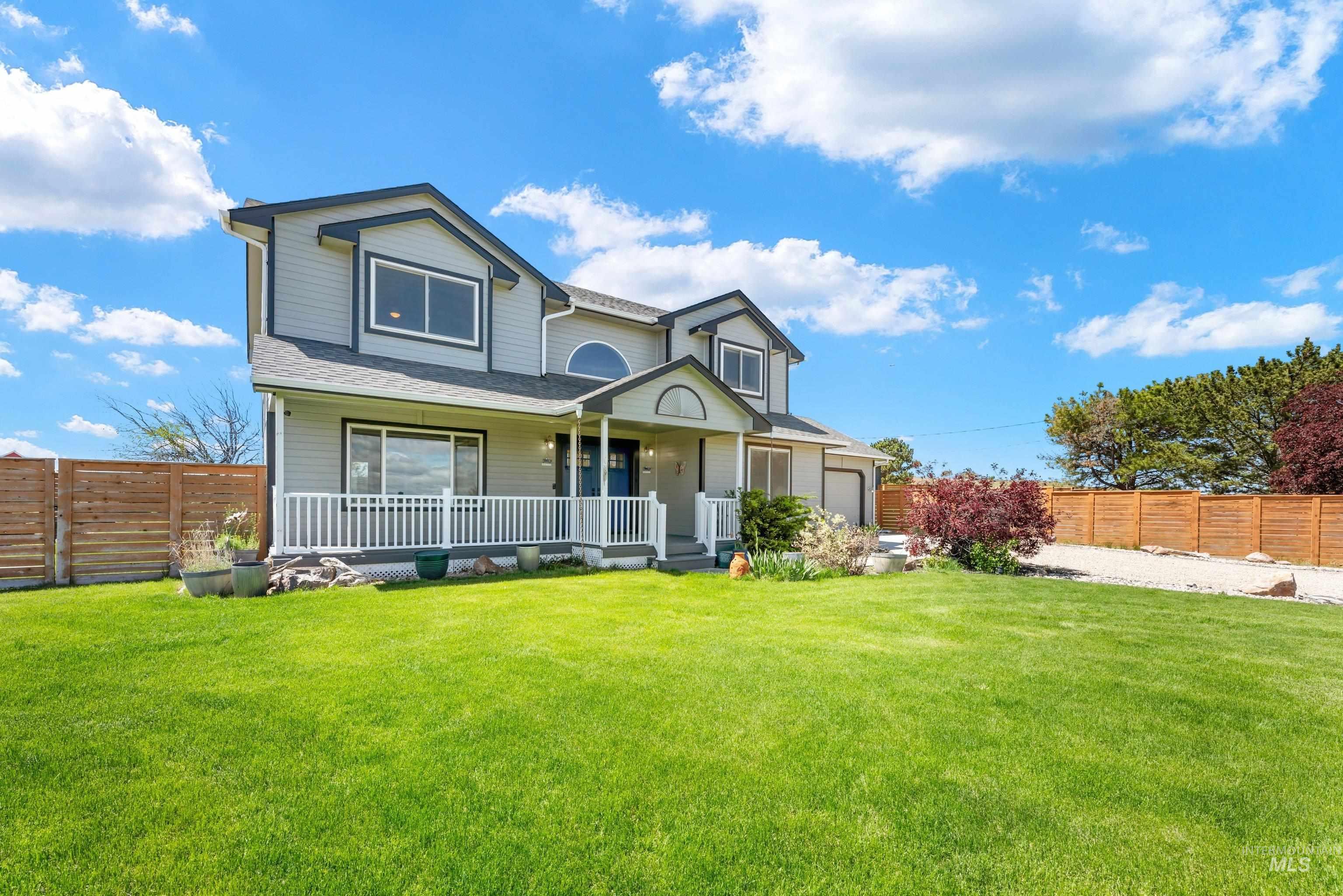 7657 Track Road Nampa, ID 83686 - Photo 39 of 49 Two-story residence featuring light gray siding with dark trim, a covered front porch with white railing, a prominent arched window, and an attached two-car garage