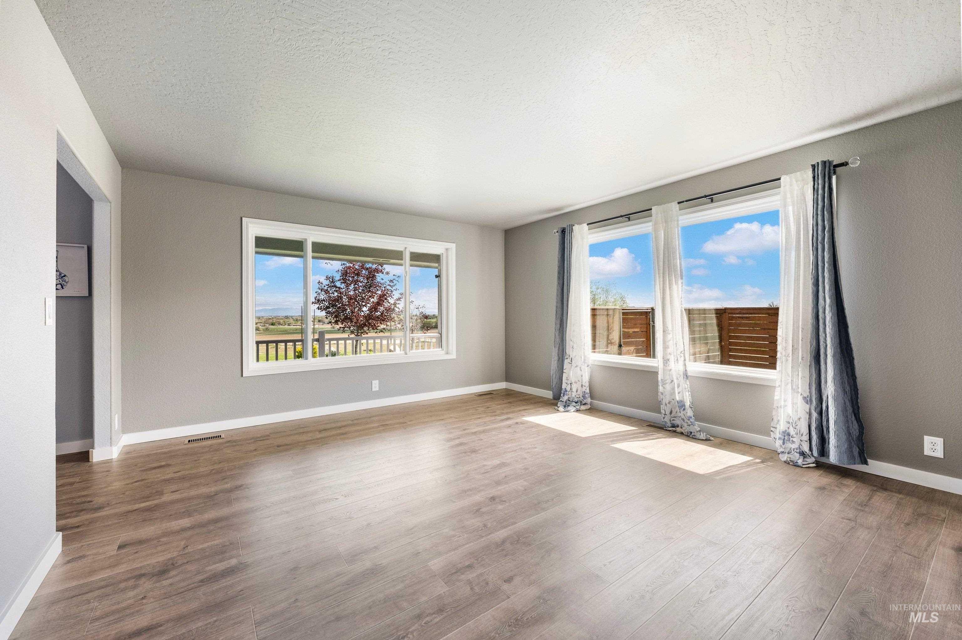 7657 Track Road Nampa, ID 83686 - Photo 6 of 49 Spacious room featuring multiple windows, wood-finish flooring, light gray walls, and white baseboards