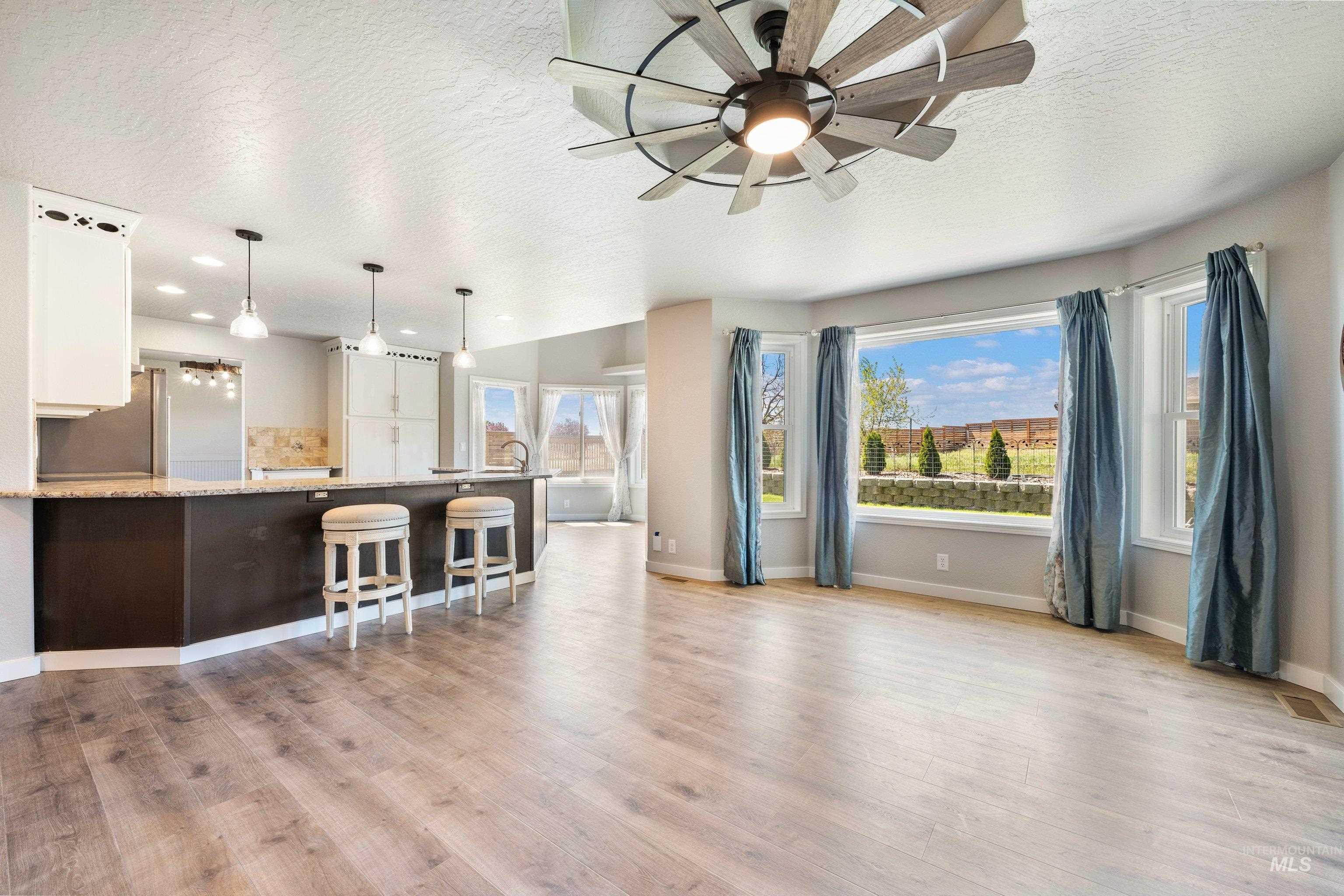 7657 Track Road Nampa, ID 83686 - Photo 10 of 49 Open-concept living space featuring wood-finish flooring, a contemporary ceiling fan with integrated lighting, and a kitchen island with pendant lighting