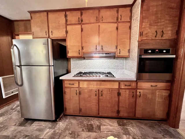 a kitchen with stainless steel appliances granite countertop a refrigerator a stove a sink and a window