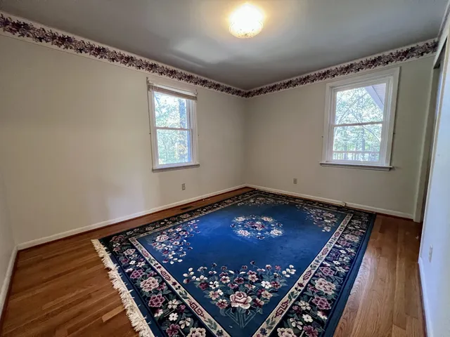 a view of an empty room with window and wooden floor