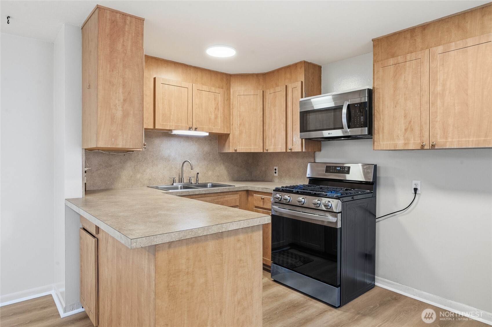 7942 15th Avenue Southwest Seattle, WA 98106 - Photo 9 of 31 a kitchen with stainless steel appliances a stove a sink a microwave a refrigerator and cabinets