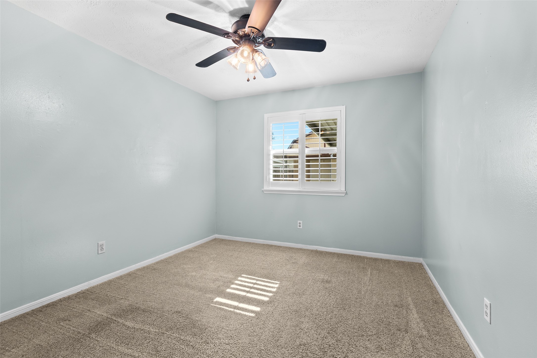 4826 Stonebridge Street Baytown, TX 77521 - Photo 10 of 18 This bedroom features soft carpeting, custom paint, a ceiling fan, and a window, creating a comfortable and well-lit space.