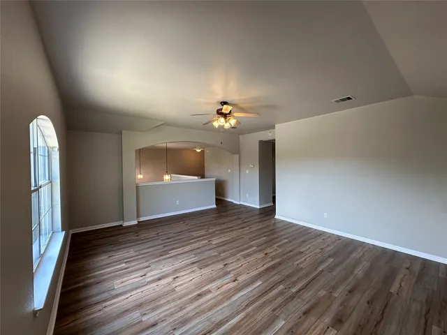 a view of a room with a ceiling fan window and wooden floor