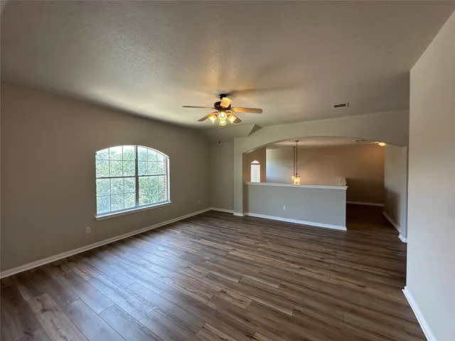 a view of an empty room with a window and wooden floor