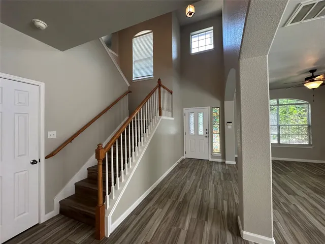 a view of an entryway with wooden floor leading to a furnished livingroom and windows