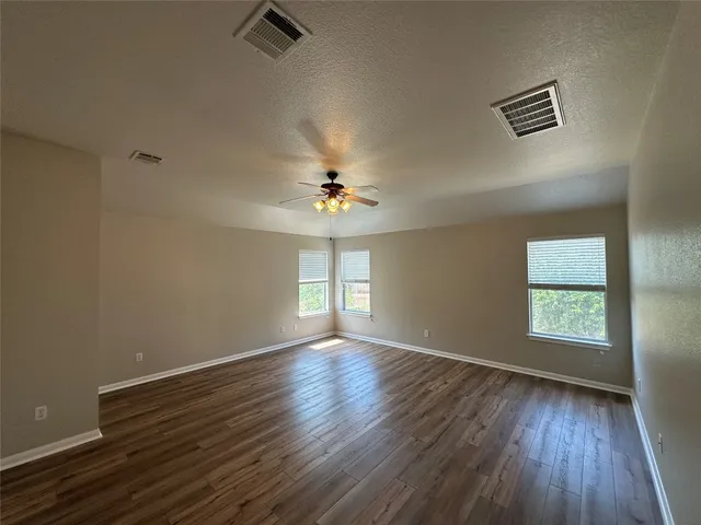 a view of an empty room with a window and wooden floor
