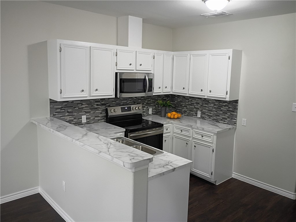 1652 16th Street Corpus Christi, TX 78404 - Photo 6 of 19 a kitchen with granite countertop white cabinets sink and stainless steel appliances