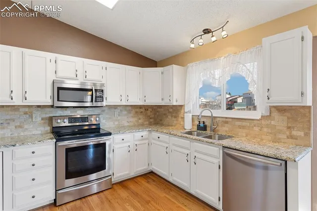 a kitchen with white cabinets stainless steel appliances and sink