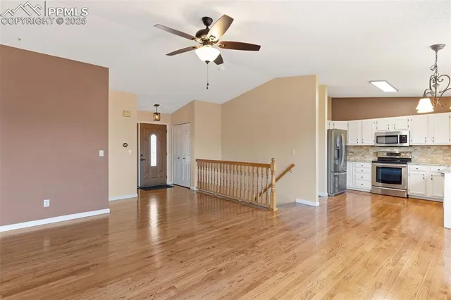 a view of an empty room with a kitchen and wooden floor