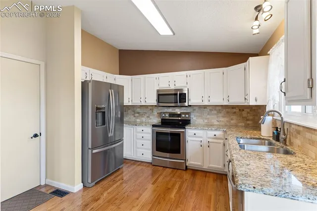 a kitchen with stainless steel appliances granite countertop a refrigerator a stove top oven a sink and dishwasher