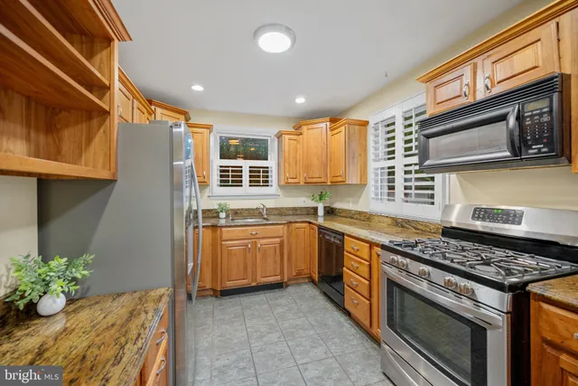 a kitchen with stainless steel appliances granite countertop a stove a sink and a microwave