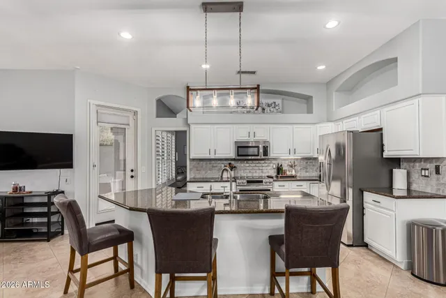 a kitchen with stainless steel appliances a refrigerator a stove a sink dishwasher a dining table and chairs with wooden floor