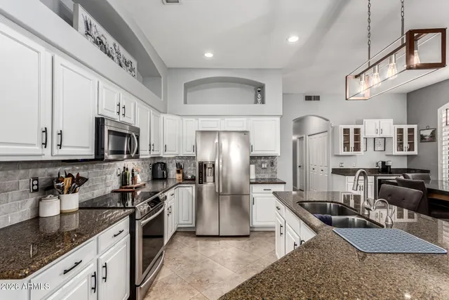 a kitchen with stainless steel appliances granite countertop a sink a stove and a refrigerator