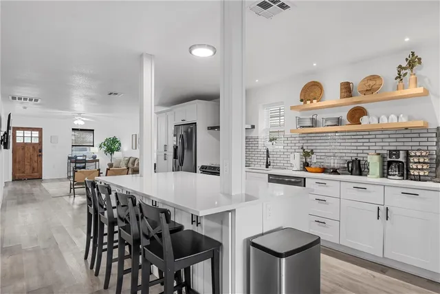 a kitchen with stainless steel appliances kitchen island granite countertop a table chairs and a refrigerator