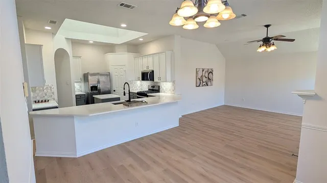 a large room with a large bed chandelier and kitchen view