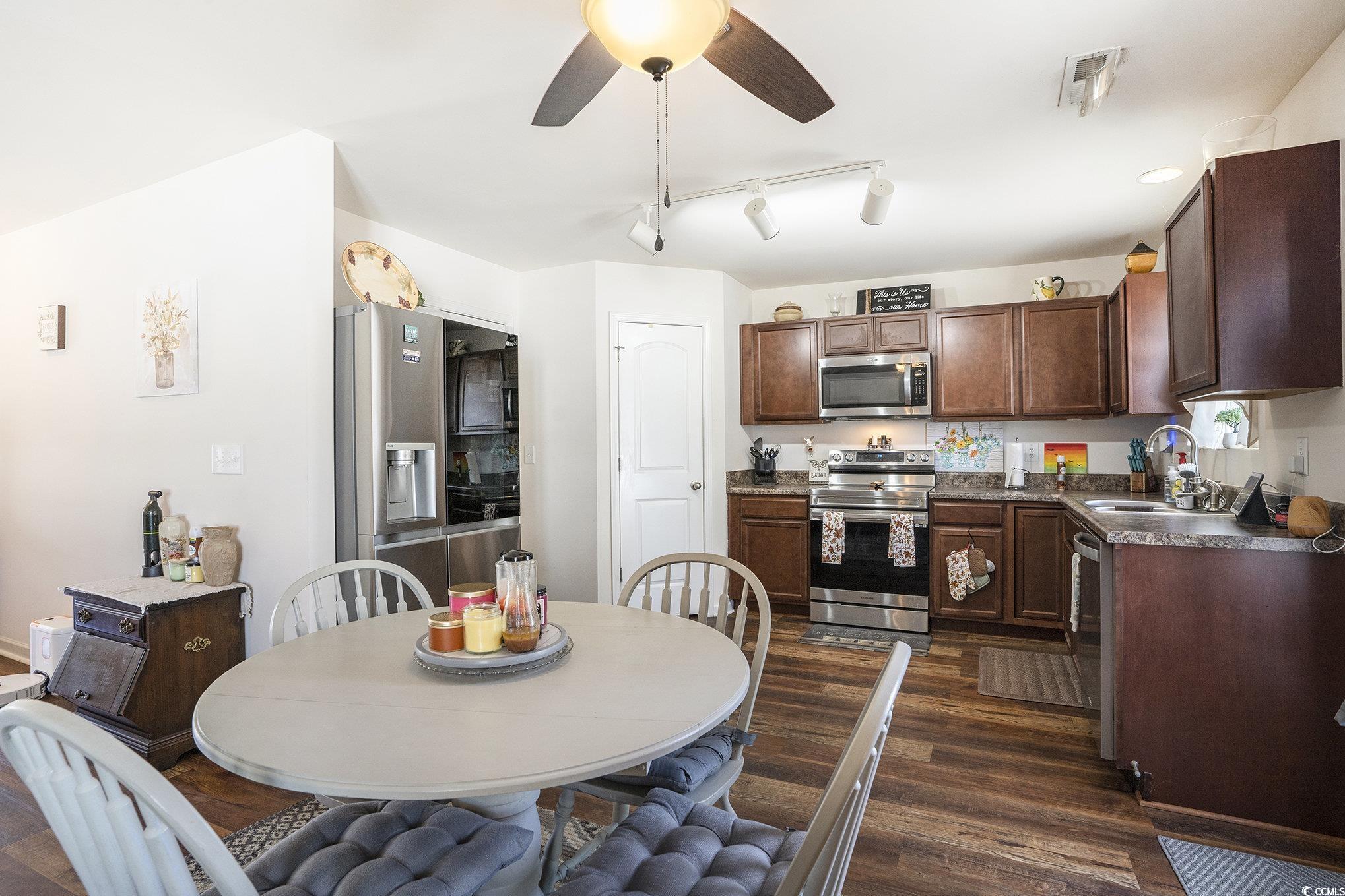 763 Trap Shooter Circle Longs, SC 29568 - Photo 11 of 37 Kitchen with dark countertops, stainless steel appliances, dark brown cabinetry, rail lighting, and dark wood finished floors