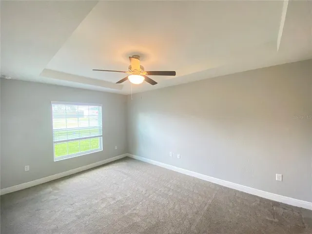 an empty room with windows and chandelier fan