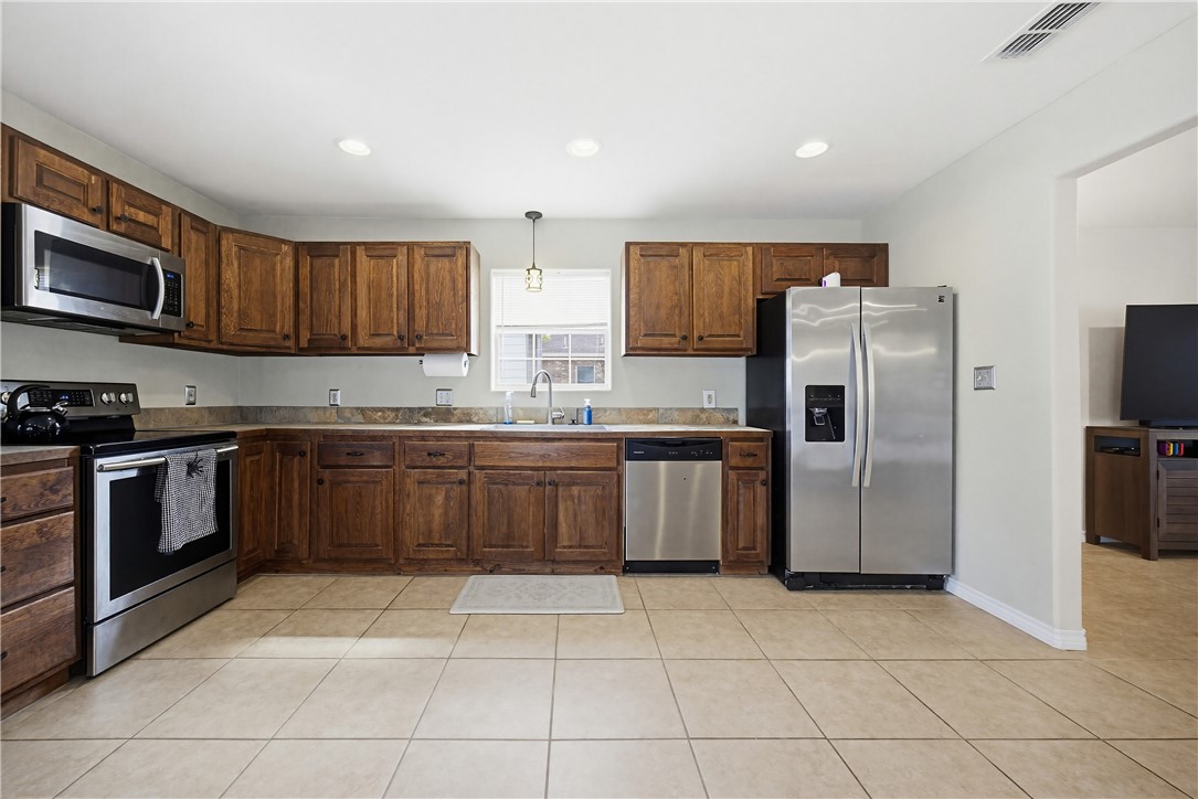 234 East Trant Road Kingsville, TX 78363 - Photo 11 of 32 a kitchen with stainless steel appliances granite countertop a stove a sink dishwasher a refrigerator and a microwave