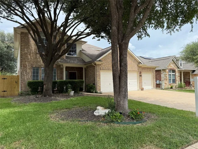 a front view of a house with garden and trees