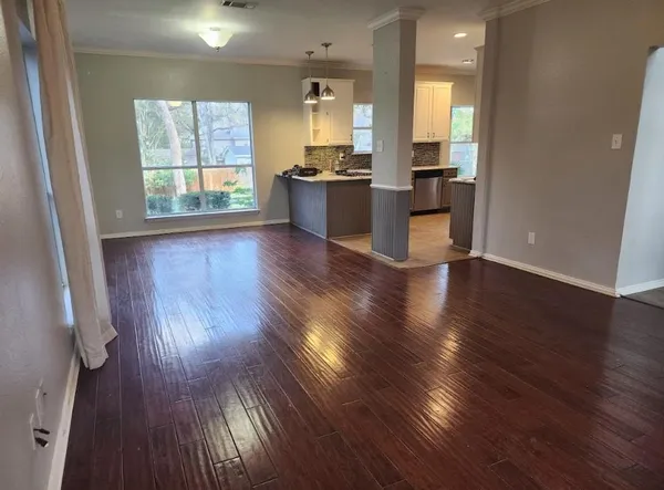 an empty room with wooden floor and windows