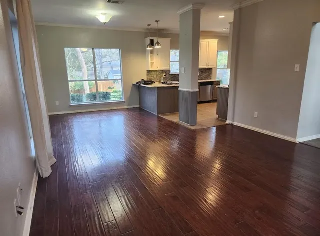 an empty room with wooden floor and windows