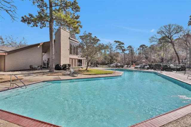 a view of swimming pool with outdoor seating and house in the background