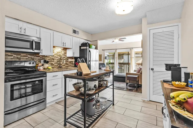 a kitchen with stainless steel appliances kitchen island granite countertop a stove top oven a sink a dining table and chairs