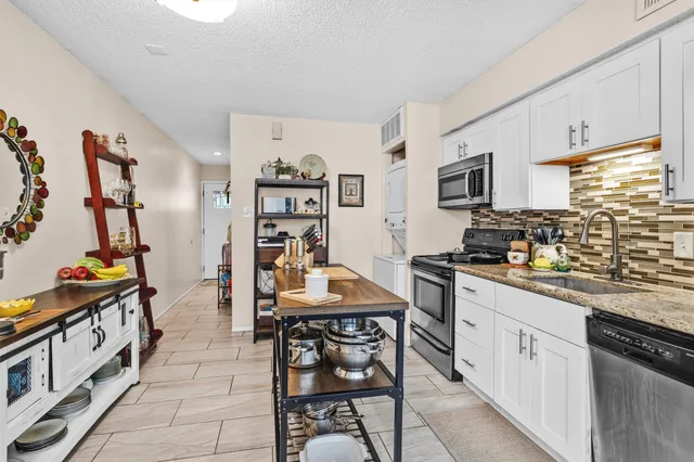 a kitchen with stainless steel appliances a stove top oven a sink a dining table and chairs