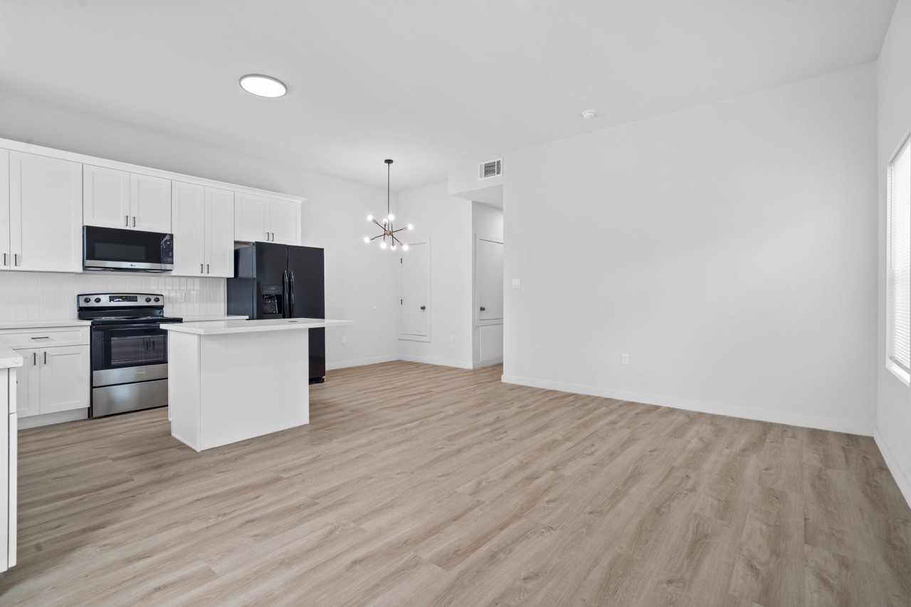 9725 Kerr Street, Unit A Houston, TX 77029 - Photo 4 of 34 Open-concept living and kitchen area featuring bright finishes, stylish flooring, pendant lighting, and a central island that anchors the main living space.