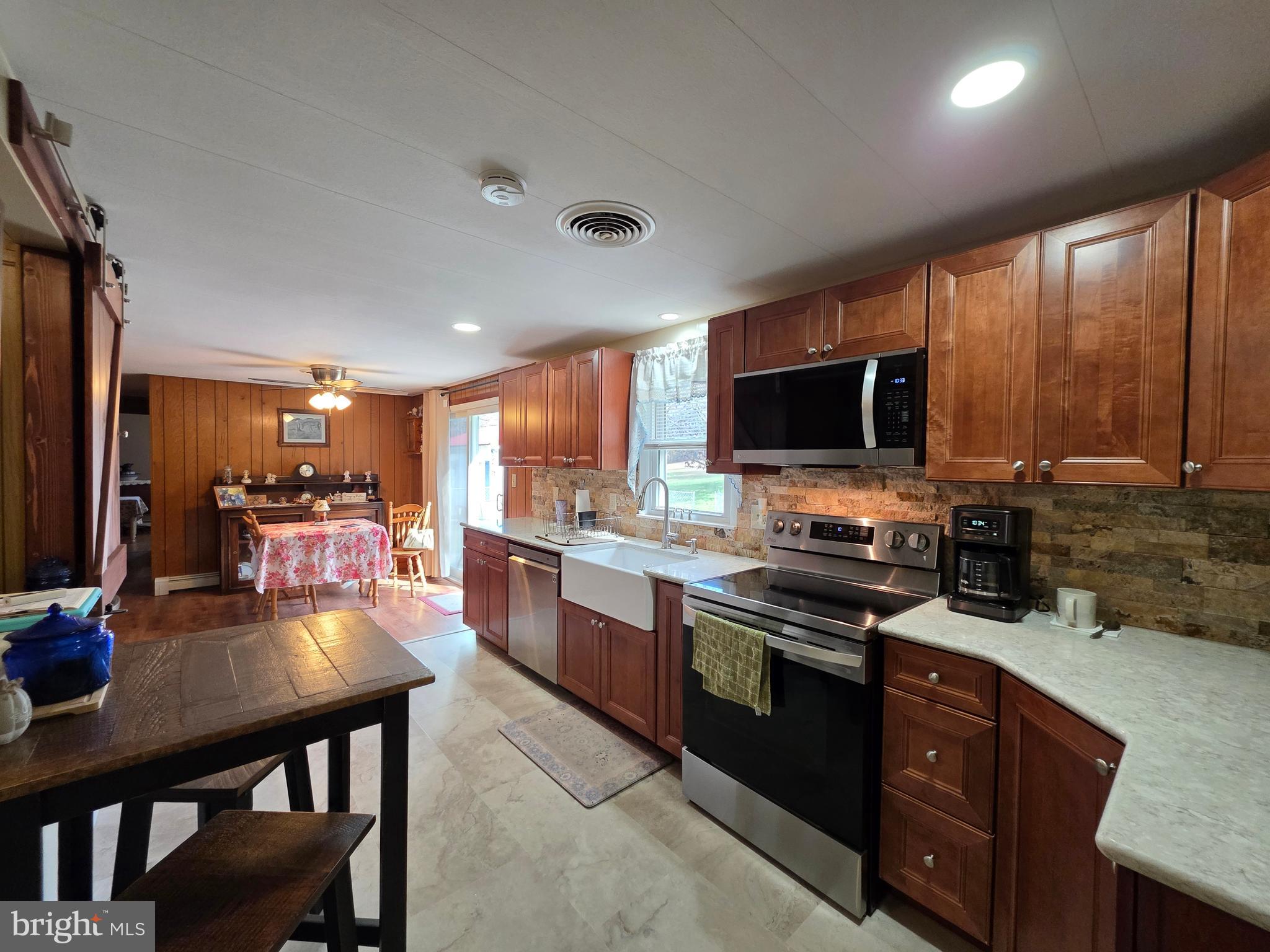 951 Johnsons Mill Road Berkeley Springs, WV 25411 - Photo 3 of 66 a kitchen with stainless steel appliances granite countertop a stove top oven a sink dishwasher a dining table and chairs with wooden floor