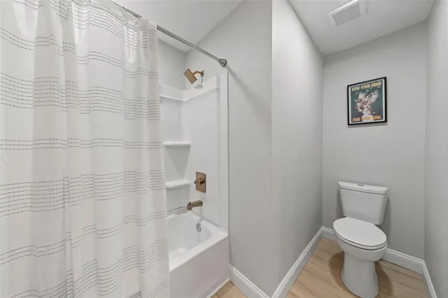 a white toilet sitting next to a bath tub