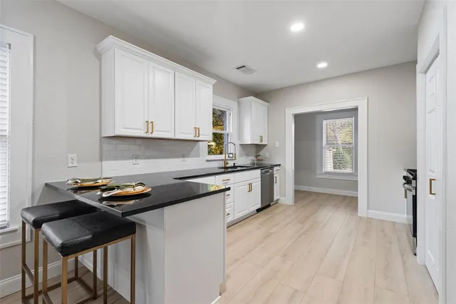 a kitchen with granite countertop a sink cabinets and wooden floor