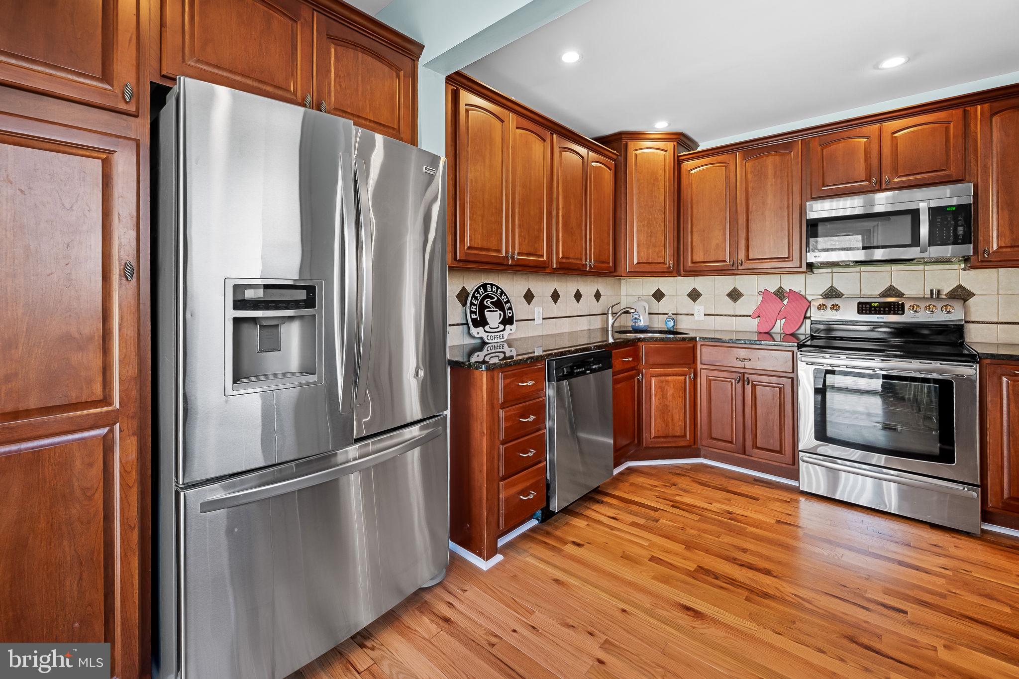 7922 Underhill Road Rosedale, MD 21237 - Photo 12 of 41 a kitchen with stainless steel appliances granite countertop a refrigerator a stove top oven a sink and dishwasher with wooden floor