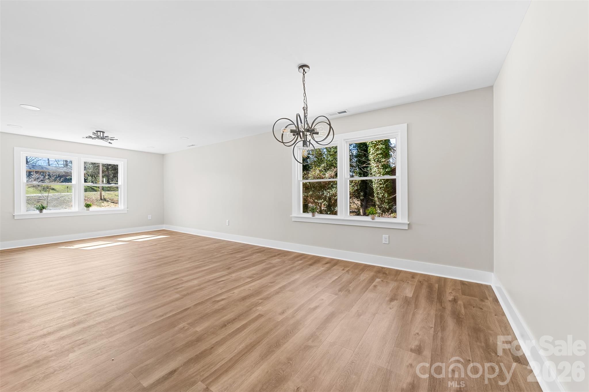 205 Redding Road Stanley, NC 28164 - Photo 12 of 34 an empty room with wooden floor chandelier and windows