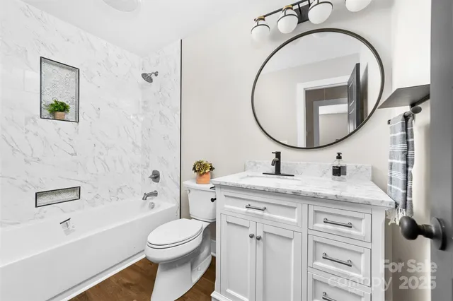 a bathroom with a granite countertop toilet sink and mirror
