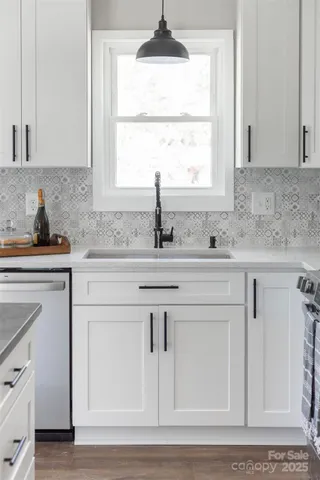 a kitchen with white cabinets and a window