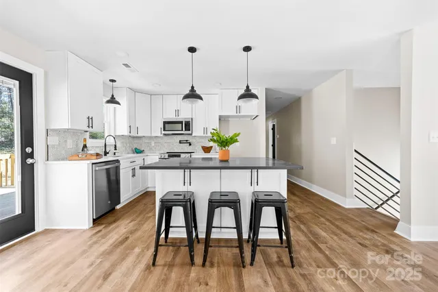 a kitchen with stainless steel appliances a dining table chairs and wooden floor