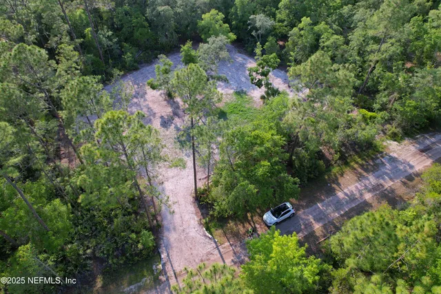 an aerial view of residential house with outdoor space and trees all around