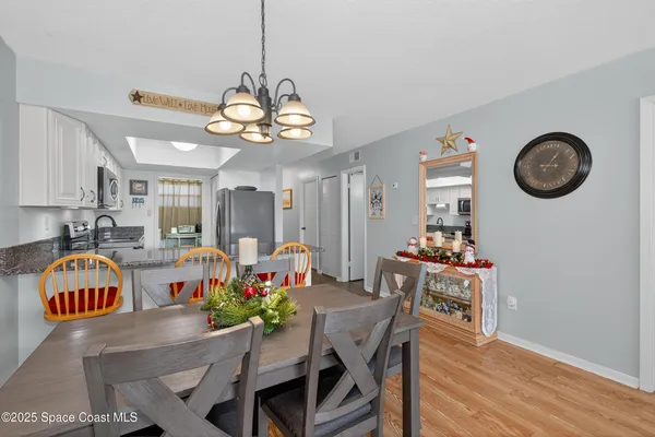 a view of a dining room and kitchen with furniture wooden floor and a chandelier