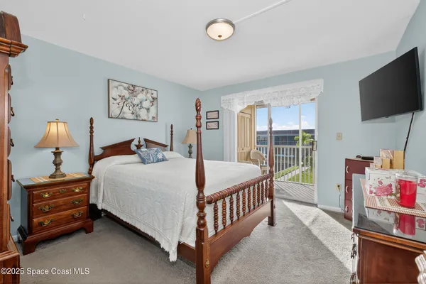 a bedroom with a bed and a flat tv screen on the dresser